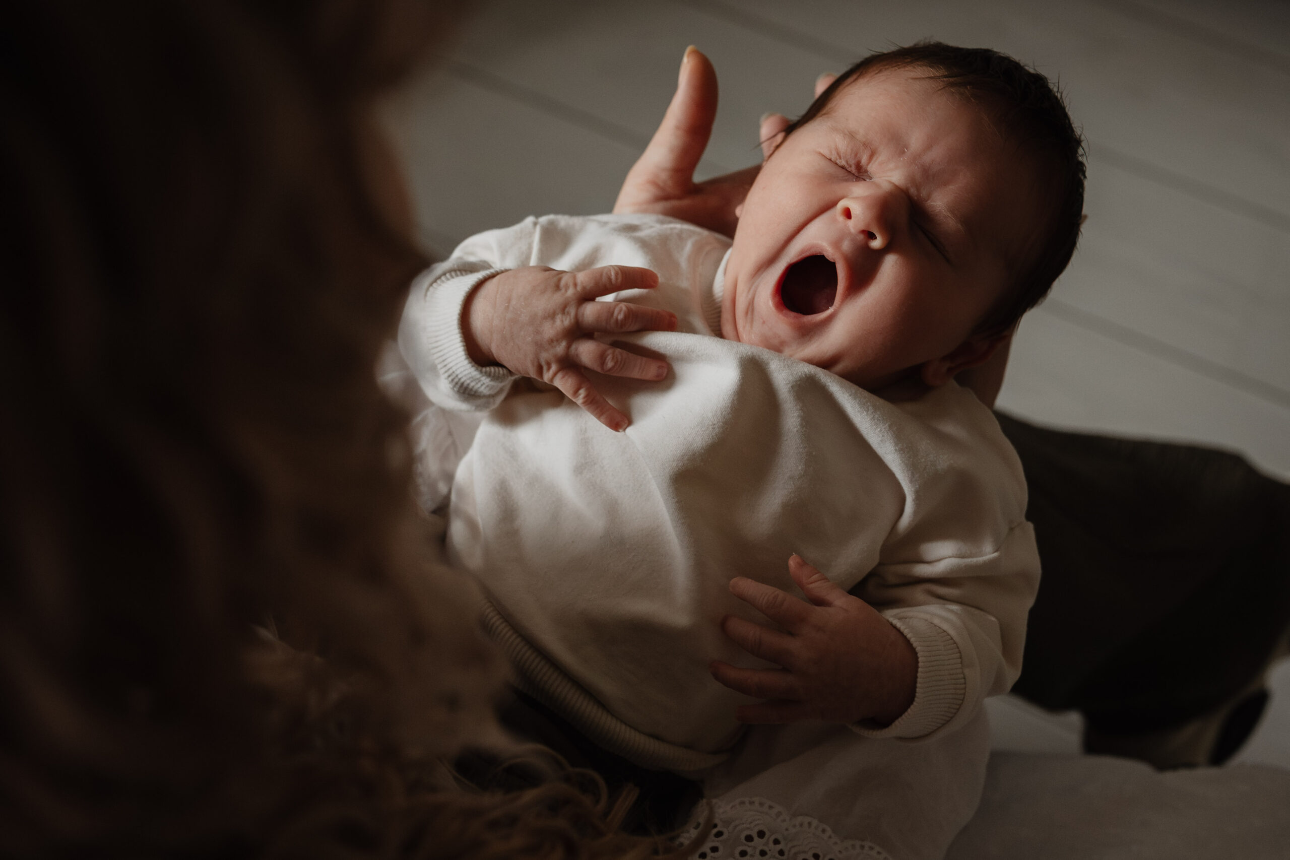 Zwangere vrouw in zacht licht, handen om haar buik